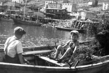 015: Two young boys in a dory. House top left is Albert Ryan's; house below it is his brother Mike's; house back center is Denis Ryan's, brother of Albert and Mike; houses at center are Dave Ryan's (left) and his brother Denis Ryan's (right); the stages at front center are Denis and Dave Ryan's. The house at right is Dave Barry's. The boy at right in the dory might be one of Mae (Dunphy) Ryan's sons, either Pat or Bill; if so, the photo would date to 1930-1935. [courtesy of Madonna (Healey) McCarthy]